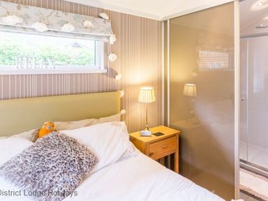 A bedroom with a bed a bedside table with lamp and a window with the word RELAX at Sheffield Pike Lodge Ullswater 8 Limefitt Park near Windermere