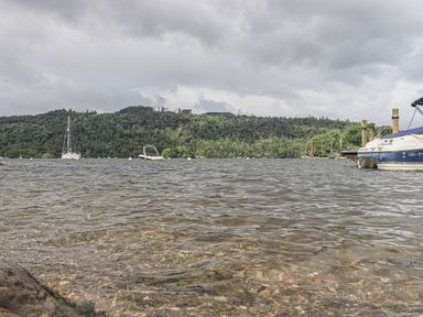 A lake with boats on the water and forested hills in the background at Shoreside Lodge L8 Fallbarrow Park near Bowness on Windermere