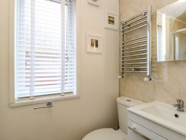 A bathroom with a toilet sink mirror towel radiator and window blinds at Shoreside Lodge L8 Fallbarrow Park near Bowness on Windermere