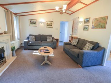 A living room with two sofas a round wooden coffee table and a fireplace at Walkers Retreat Lodge Fellside 5 Limefitt Park near Windermere
