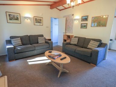 A living room with two gray sofas a wooden coffee table maps and pictures on the walls at Walkers Retreat Lodge in Fellside 5 Limefitt Park near Windermere