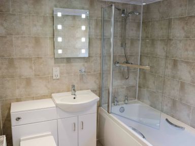 A bathroom with a sink vanity unit a toilet a bathtub with a shower screen and a wall-mounted shower at Walkers Retreat Lodge Fellside 5 Limefitt Park near Windermere