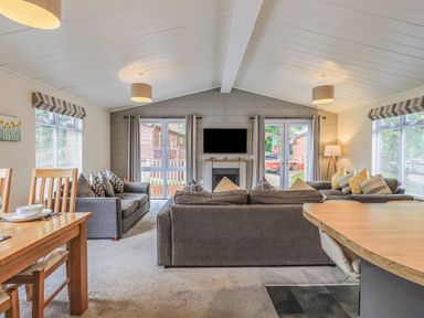 A living room with sofas and a TV above a fireplace at Daffodils Lodge Oakside 7 Fallbarrow Park in Bowness on Windermere