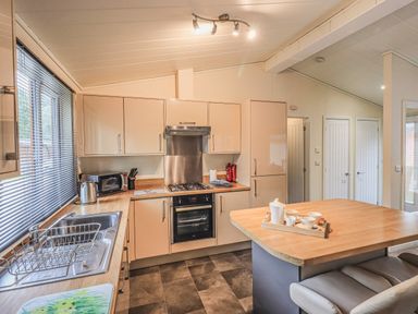 A kitchen with appliances and a breakfast bar at Daffodils Lodge Oakside 7 Fallbarrow Park in Bowness on Windermere