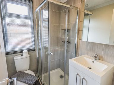 A bathroom with a toilet towel and shower cubicle next to a white sink with cabinet at Daffodils Lodge Oakside 7 Fallbarrow Park in Bowness on Windermere