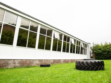 An exterior view of a building with large windows and two large tires on the grass in front of it at Daffodils Lodge Oakside 7 Fallbarrow Park in Bowness on Windermere