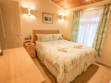 A bedroom with a double bed bedside tables and curtains at Tanglewood Lodge Thirlmere 15 White Cross Bay near Windermere