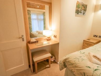 A bedroom with a dressing table chair lamp and bed at Tanglewood Lodge Thirlmere 15 White Cross Bay near Windermere