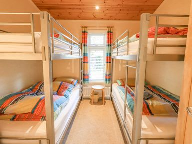 A bedroom with two bunk beds and a small round table between them at Tanglewood Lodge Thirlmere 15 White Cross Bay near Windermere