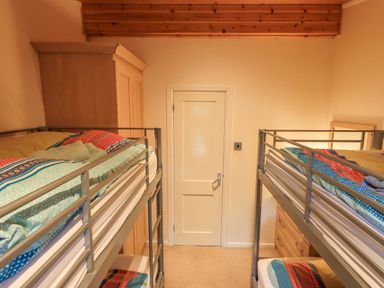 A bedroom with two metal bunk beds and a wooden wardrobe at Tanglewood Lodge Thirlmere 15 White Cross Bay near Windermere