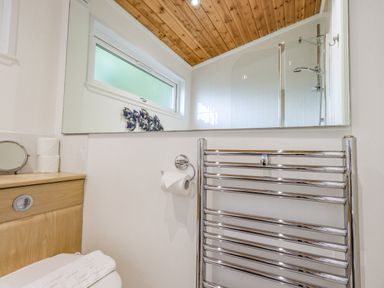 A bathroom with a toilet towel rack mirror and window at Tanglewood Lodge in Thirlmere 15 White Cross Bay near Windermere
