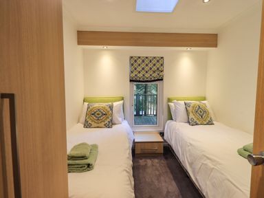 A bedroom with two single beds and a small nightstand between the beds at Forest Pines Lodge Beech Hill 10 Fallbarrow Park near Bowness on Windermere