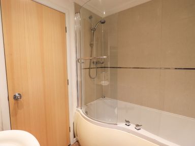 A bathroom with a bathtub shower combination and a wooden door at Forest Pines Lodge Beech Hill 10 Fallbarrow Park near Bowness on Windermere