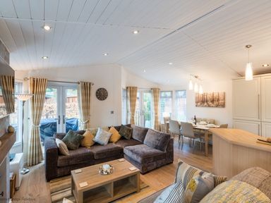 A living room with sofas a coffee table and a dining area with a table and chairs at Broad Larch Lodge in Glade 16 Fallbarrow Park near Bowness on Windermere