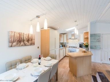 A kitchen and dining area with a table set for six and a wooden kitchen counter at Broad Larch Lodge in Glade 16 Fallbarrow Park near Bowness on Windermere