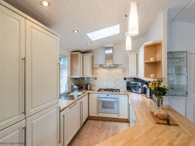 A kitchen with wooden countertops white cabinets and appliances at Broad Larch Lodge in Glade 16 Fallbarrow Park near Bowness on Windermere