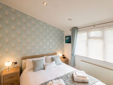 A bedroom with a double bed two bedside tables and a window with blinds at Broad Larch Lodge Glade 16 Fallbarrow Park near Bowness on Windermere