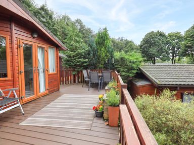 An outdoor deck with chairs and plants at Birthwaite Lodge, Fellside 6, Limefitt Park near Windermere