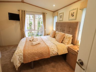 A bedroom with a double bed pillows nightstands and a window at Squirrels Snug Pony Meadow 1 White Cross Bay near Windermere