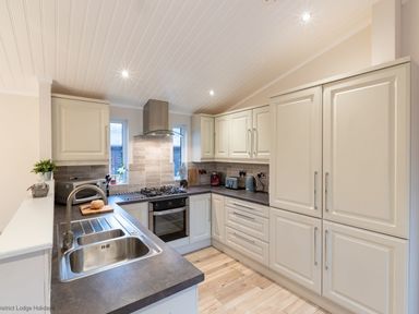 A kitchen with cream cabinets a double sink a stove and various appliances at Comraich Beckside 40 Limefitt Park near Windermere