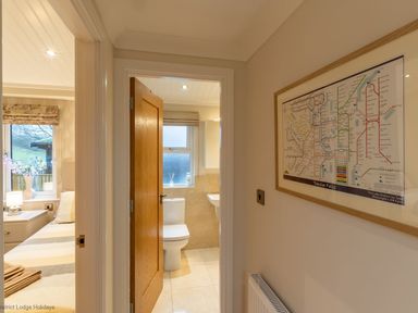 A hallway with a framed map on the wall leading to a bathroom and a bedroom at Comraich Beckside 40 Limefitt Park near Windermere