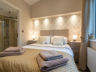 A bedroom with a bed with towels on the bed and bedside tables with lamps at Comraich Beckside 40 Limefitt Park near Windermere