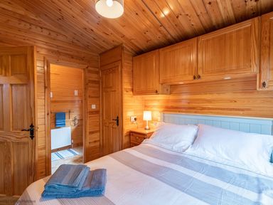 A bedroom with a bed covered with pillows and folded towels and wooden cabinets above the bed at Lakeshaven Skiptory Howe 16 White Cross Bay near Windermere