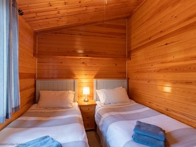 A bedroom with two single beds a bedside table with a lamp and towels on the beds at Lakeshaven Skiptory Howe 16 White Cross Bay near Windermere
