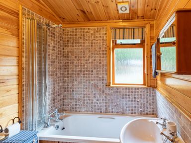 A bathroom with a bathtub sink a window and tiled walls at Lakeshaven Skiptory Howe 16 White Cross Bay near Windermere