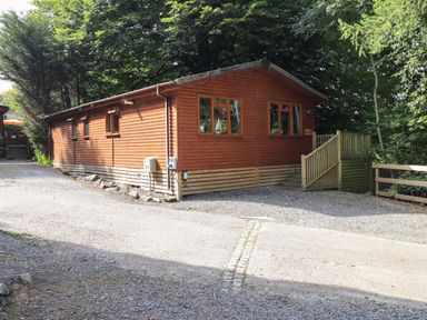A wooden cabin with windows and a small staircase surrounded by trees at Lakeshaven Skiptory Howe 16 White Cross Bay near Windermere