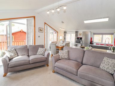 A living room with two sofas and a dining table next to a kitchen at Limefitt Lodge Fellside 8 Limefitt Park near Windermere