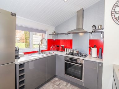 A modern kitchen with gray cabinets red backsplash and stainless steel appliances at Limefitt Lodge Fellside 8 Limefitt Park near Windermere