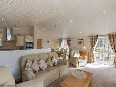 A living room with beige sofas and a wooden coffee table with a clear bowl at Waterbird Lakeview 4 White Cross Bay near Windermere