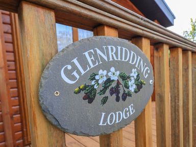 A wooden railing with a stone sign reading Glenridding Lodge with painted flowers at Glenridding Lodge Grasmere 2 White Cross Bay near Windermere