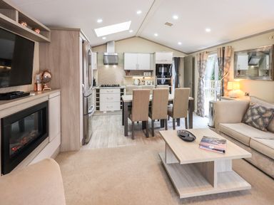 An open living room and kitchen with a dining table six chairs a sofa and a fireplace at Glenridding Lodge Grasmere 2 White Cross Bay near Windermere
