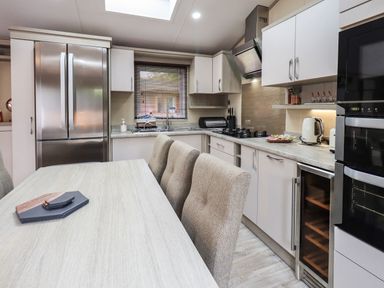 A kitchen with a dining table chairs stainless steel refrigerator oven and kettle at Glenridding Lodge Grasmere 2 White Cross Bay near Windermere
