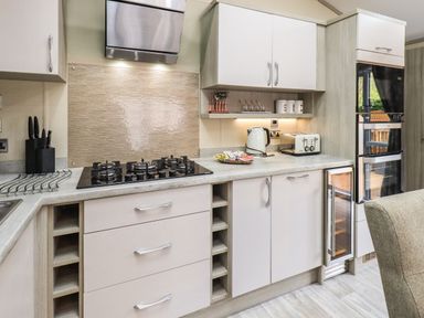 A kitchen with a gas stove kettle toaster and built in ovens at Glenridding Lodge Grasmere 2 White Cross Bay near Windermere