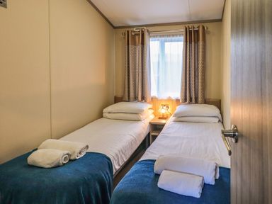 A bedroom with two single beds towels on beds and a lamp on a nightstand at Glenridding Lodge Grasmere 2 White Cross Bay near Windermere