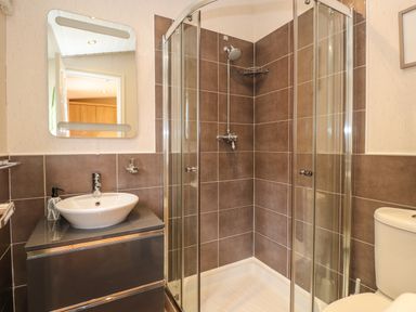 A bathroom with a shower enclosure a sink on a cabinet and a toilet at Wainwright Lodge Kirkstone 27 Limefitt Park near Windermere