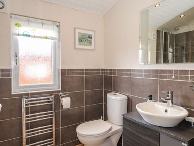A bathroom with a toilet sink mirror towel rail and a window at Wainwright Lodge Kirkstone 27 Limefitt Park near Windermere