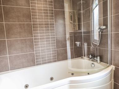 A bathroom with a bathtub shower combination and tiled walls at Wainwright Lodge Kirkstone 27 Limefitt Park near Windermere