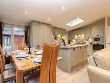 A kitchen and dining area with wooden dining table set and kitchen island at Wainwright Lodge in Kirkstone 27 Limefitt Park near Windermere