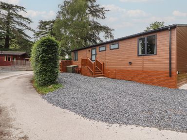 A lodge with a gravel area and steps at Beech Grove Lodge, Glade 17, Fallbarrow Park near Bowness on Windermere