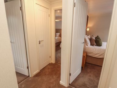 A hallway with doors leading to bedrooms at Beech Grove Lodge, Glade 17, Fallbarrow Park near Bowness on Windermere