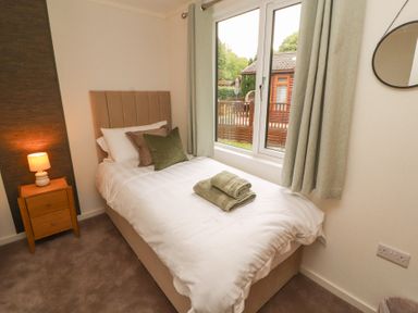 A bedroom with a bed and window at Beech Grove Lodge, Glade 17, Fallbarrow Park near Bowness on Windermere