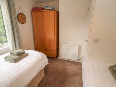 A bedroom with two beds and a wardrobe at Beech Grove Lodge, Glade 17, Fallbarrow Park near Bowness on Windermere