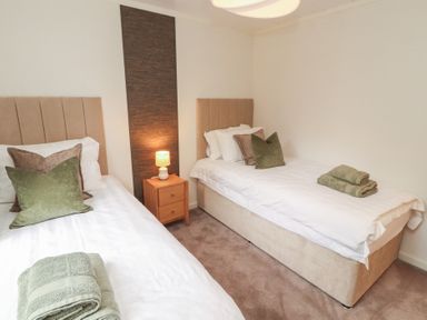 A bedroom with two single beds and a nightstand at Beech Grove Lodge, Glade 17, Fallbarrow Park near Bowness on Windermere
