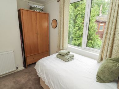 A bedroom with a bed and wardrobe at Beech Grove Lodge, Glade 17, Fallbarrow Park near Bowness on Windermere