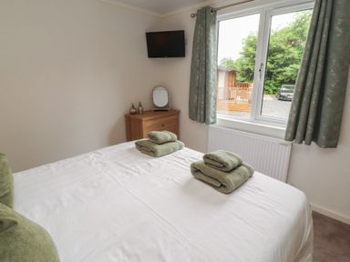 A bedroom with bed and towels on top at Beech Grove Lodge near Glade 17, Fallbarrow Park near Bowness on Windermere