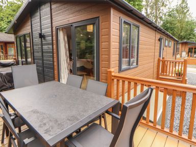An outdoor dining area with a table and chairs at Beech Grove Lodge, Glade 17, Fallbarrow Park near Bowness on Windermere